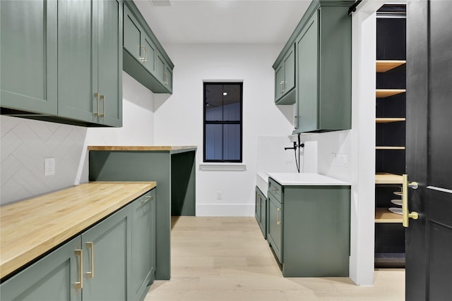 kitchen with baseboards, green cabinets, wooden counters, light wood-style floors, and tasteful backsplash