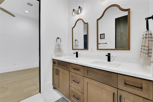 bathroom featuring double vanity, visible vents, a sink, and wood finished floors