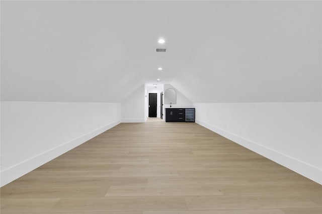 additional living space featuring vaulted ceiling, light wood finished floors, visible vents, and baseboards