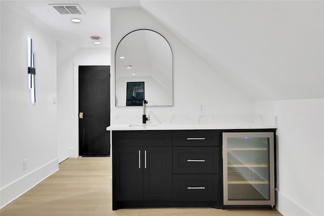 bar featuring beverage cooler, light wood-type flooring, lofted ceiling, and visible vents