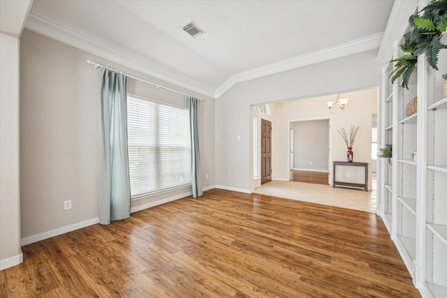 empty room with lofted ceiling, hardwood / wood-style floors, a notable chandelier, and ornamental molding