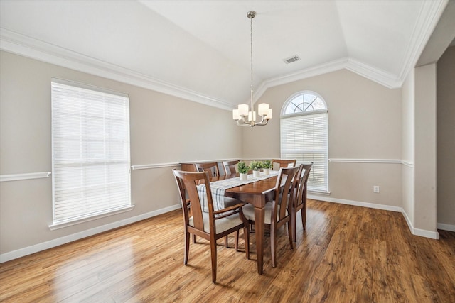 dining area with hardwood / wood-style flooring, vaulted ceiling, ornamental molding, and a notable chandelier