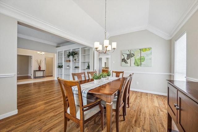 dining area with lofted ceiling, hardwood / wood-style floors, crown molding, and a chandelier