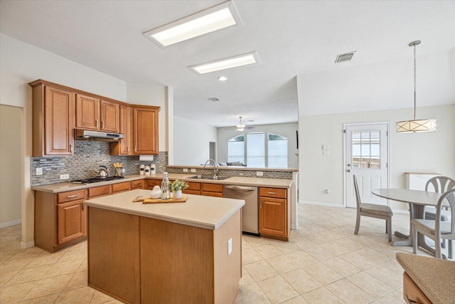 kitchen featuring appliances with stainless steel finishes, pendant lighting, sink, decorative backsplash, and kitchen peninsula