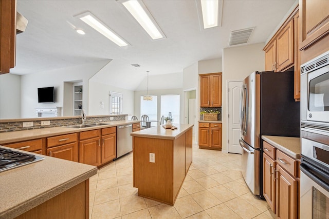 kitchen featuring sink, appliances with stainless steel finishes, tasteful backsplash, a kitchen island, and decorative light fixtures