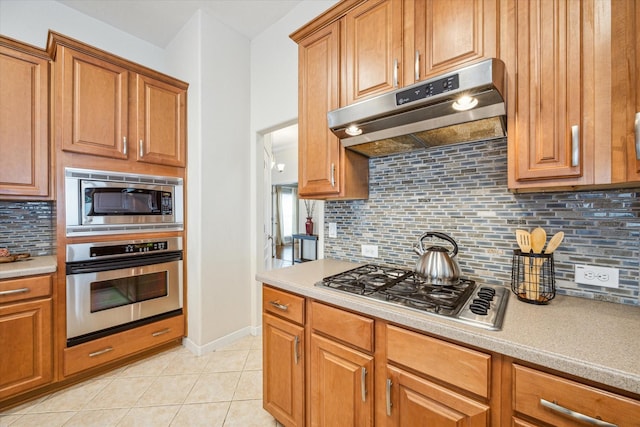 kitchen with appliances with stainless steel finishes, decorative backsplash, and light tile patterned floors