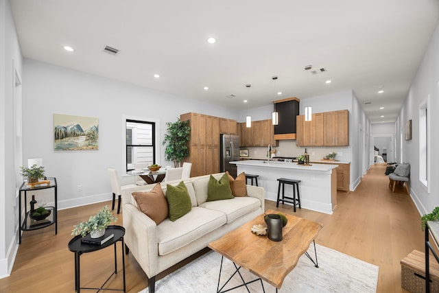 living room with light wood-type flooring, visible vents, baseboards, and recessed lighting