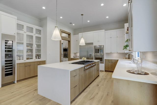 kitchen with a large island, sink, white cabinets, and built in appliances