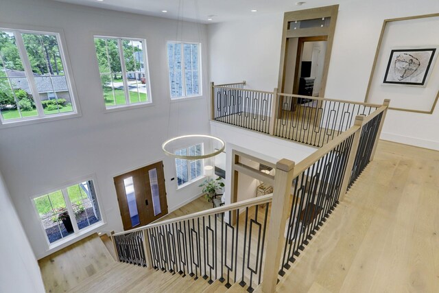 staircase with hardwood / wood-style floors and a towering ceiling