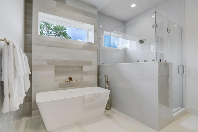 bathroom featuring plus walk in shower and tile walls