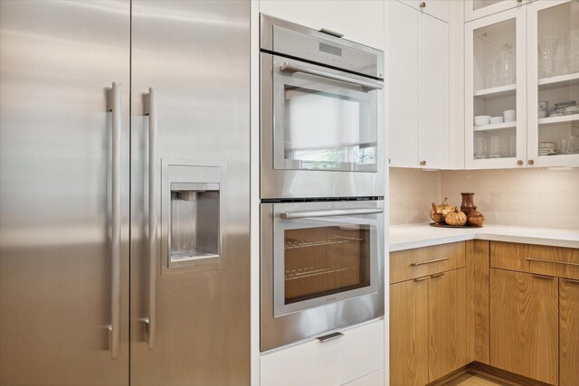 kitchen with tasteful backsplash, white cabinetry, and appliances with stainless steel finishes