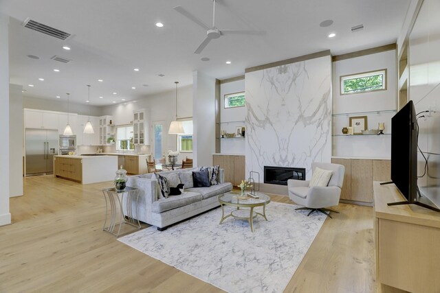 living room featuring a towering ceiling, a fireplace, light hardwood / wood-style floors, and a wealth of natural light