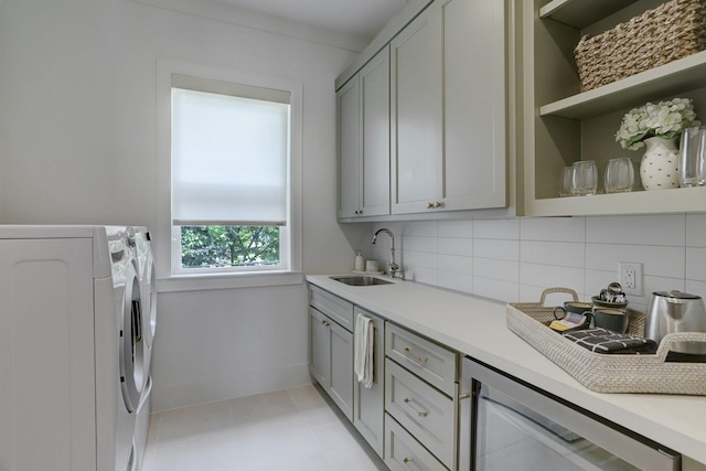 washroom with wine cooler, sink, cabinets, light tile patterned floors, and washer and clothes dryer