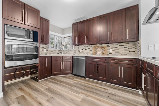 kitchen with backsplash, stainless steel appliances, and light wood-type flooring