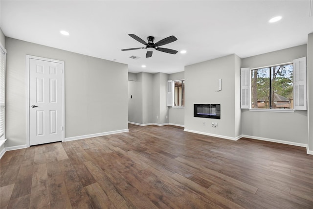 unfurnished living room featuring dark wood-type flooring and ceiling fan