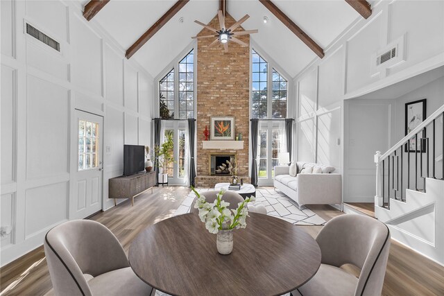 dining area featuring a brick fireplace, hardwood / wood-style flooring, high vaulted ceiling, and beamed ceiling