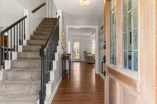 foyer entrance with dark wood-type flooring and a textured ceiling