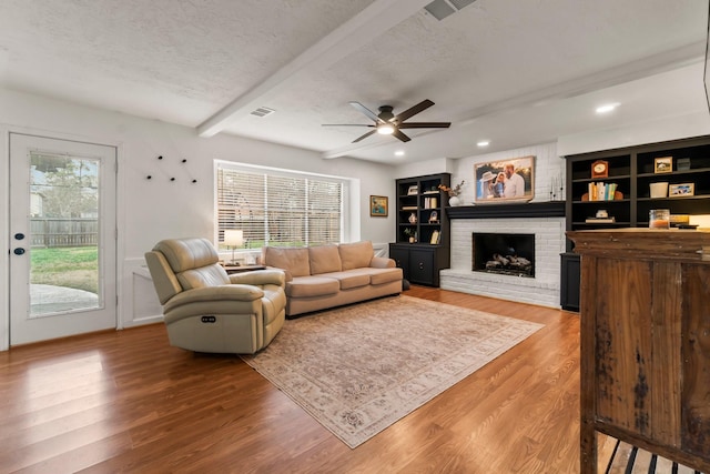 living room with beamed ceiling, a healthy amount of sunlight, hardwood / wood-style floors, and a textured ceiling