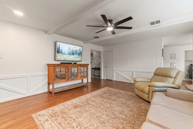 living room with beamed ceiling, wood-type flooring, and ceiling fan