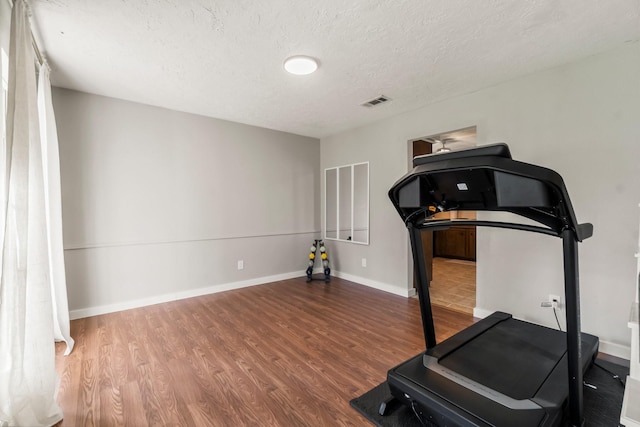 exercise room featuring hardwood / wood-style flooring and a textured ceiling