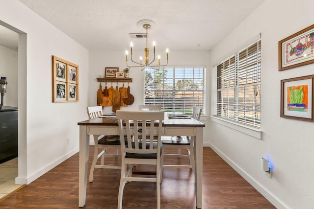 dining room with dark hardwood / wood-style floors, a textured ceiling, and a chandelier