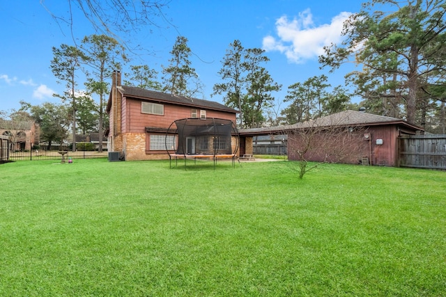 rear view of property with a trampoline, cooling unit, and a yard