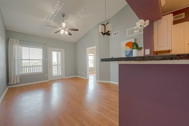 interior space featuring high vaulted ceiling, ceiling fan with notable chandelier, a wealth of natural light, and light wood-type flooring