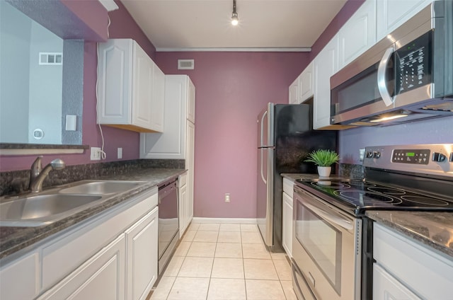 kitchen with light tile patterned flooring, rail lighting, sink, white cabinetry, and stainless steel appliances