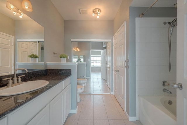 full bathroom with tile patterned flooring, vanity, tiled shower / bath combo, and toilet