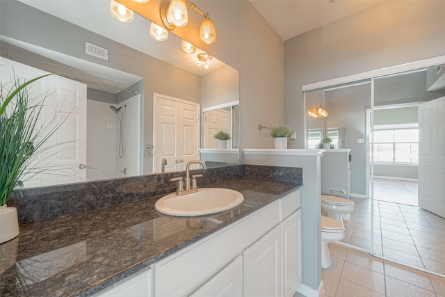 bathroom featuring a tile shower, vanity, tile patterned floors, and toilet