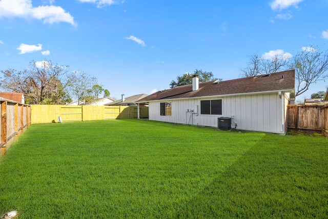 back of house with central AC unit and a lawn