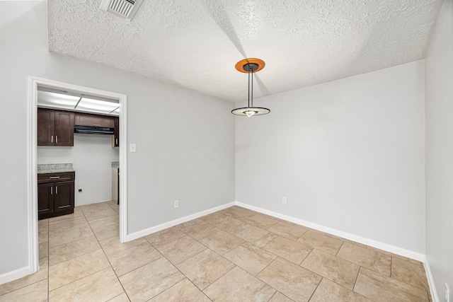 unfurnished dining area featuring a textured ceiling and light tile patterned floors