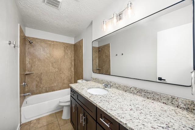 full bathroom with tiled shower / bath, vanity, toilet, tile patterned floors, and a textured ceiling