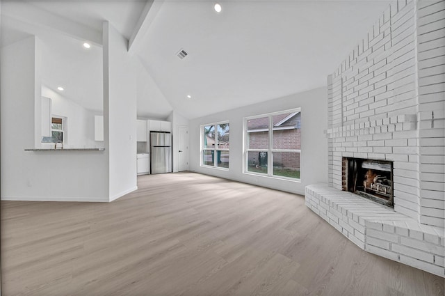 unfurnished living room featuring beamed ceiling, a fireplace, high vaulted ceiling, and light wood-type flooring