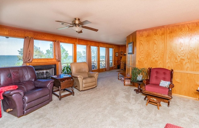 carpeted living room featuring ceiling fan and wood walls