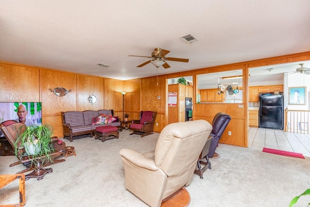 living room featuring light carpet, ceiling fan, and wood walls