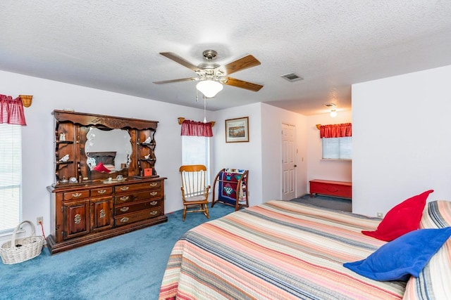 bedroom featuring ceiling fan, carpet floors, and a textured ceiling