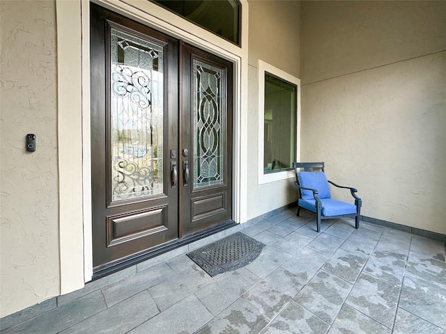 view of exterior entry featuring french doors and stucco siding