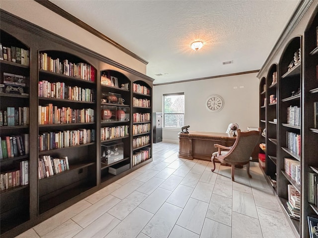 interior space with a textured ceiling, ornamental molding, wall of books, and visible vents