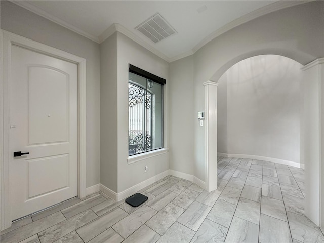 foyer entrance with arched walkways, visible vents, crown molding, and baseboards