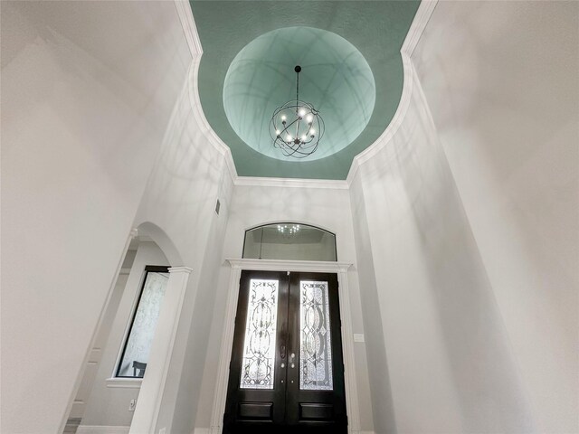 entrance foyer featuring a notable chandelier, ornamental molding, french doors, and a high ceiling