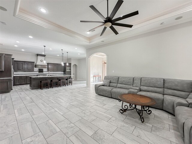 living room featuring crown molding, a tray ceiling, and ceiling fan