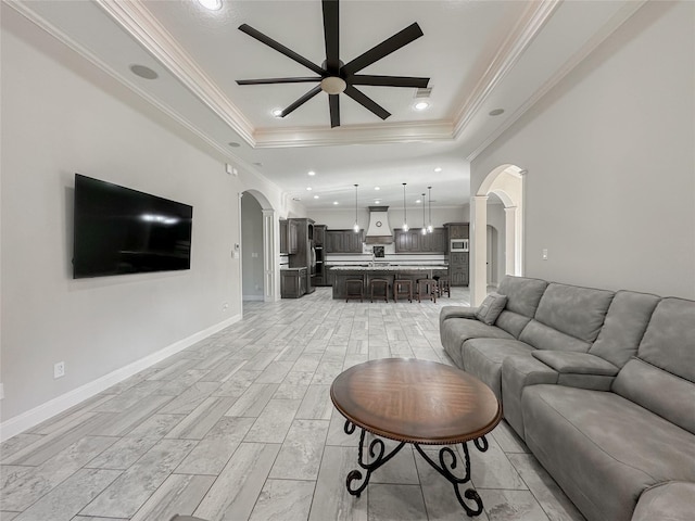 living room with crown molding, a tray ceiling, and ceiling fan