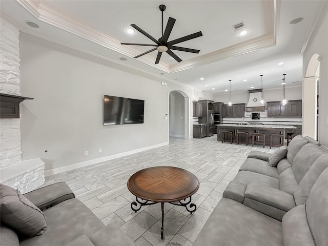 living room featuring a raised ceiling, ornamental molding, and ceiling fan