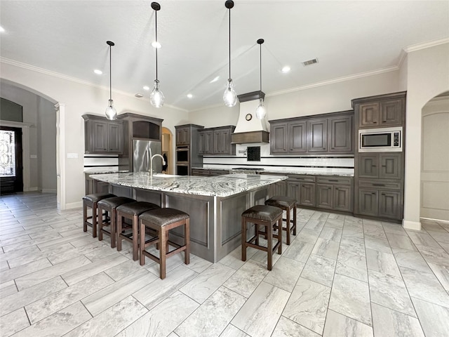 kitchen with pendant lighting, stainless steel appliances, a breakfast bar, and a large island with sink