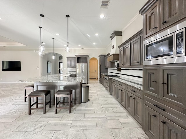 kitchen featuring light stone counters, arched walkways, stainless steel appliances, visible vents, and a sink