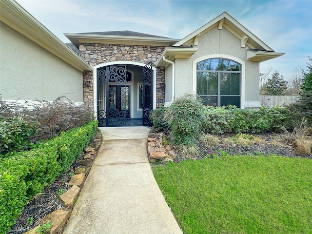 view of exterior entry featuring stone siding, fence, and stucco siding