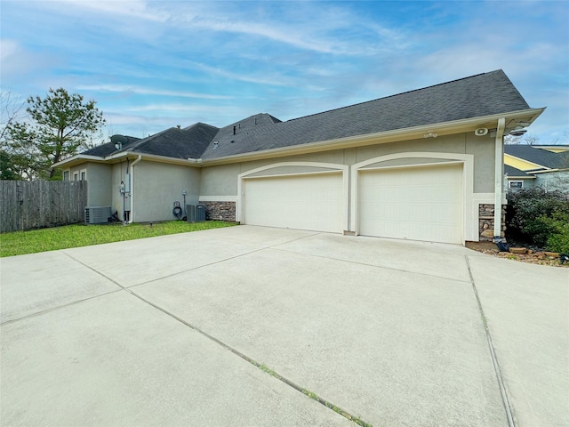 view of front of home featuring stone siding, central AC unit, concrete driveway, and stucco siding