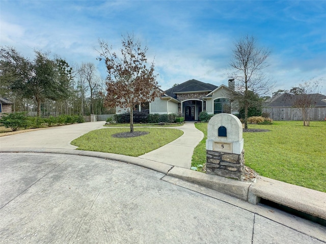 view of front of home featuring a chimney, a front yard, fence, stone siding, and driveway