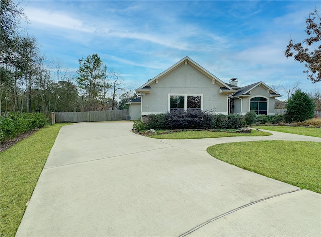 view of front of property featuring concrete driveway, fence, a front lawn, and stucco siding